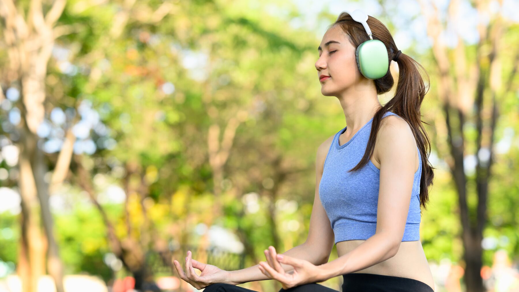 A woman meditating outdoors among trees in soft daylight
