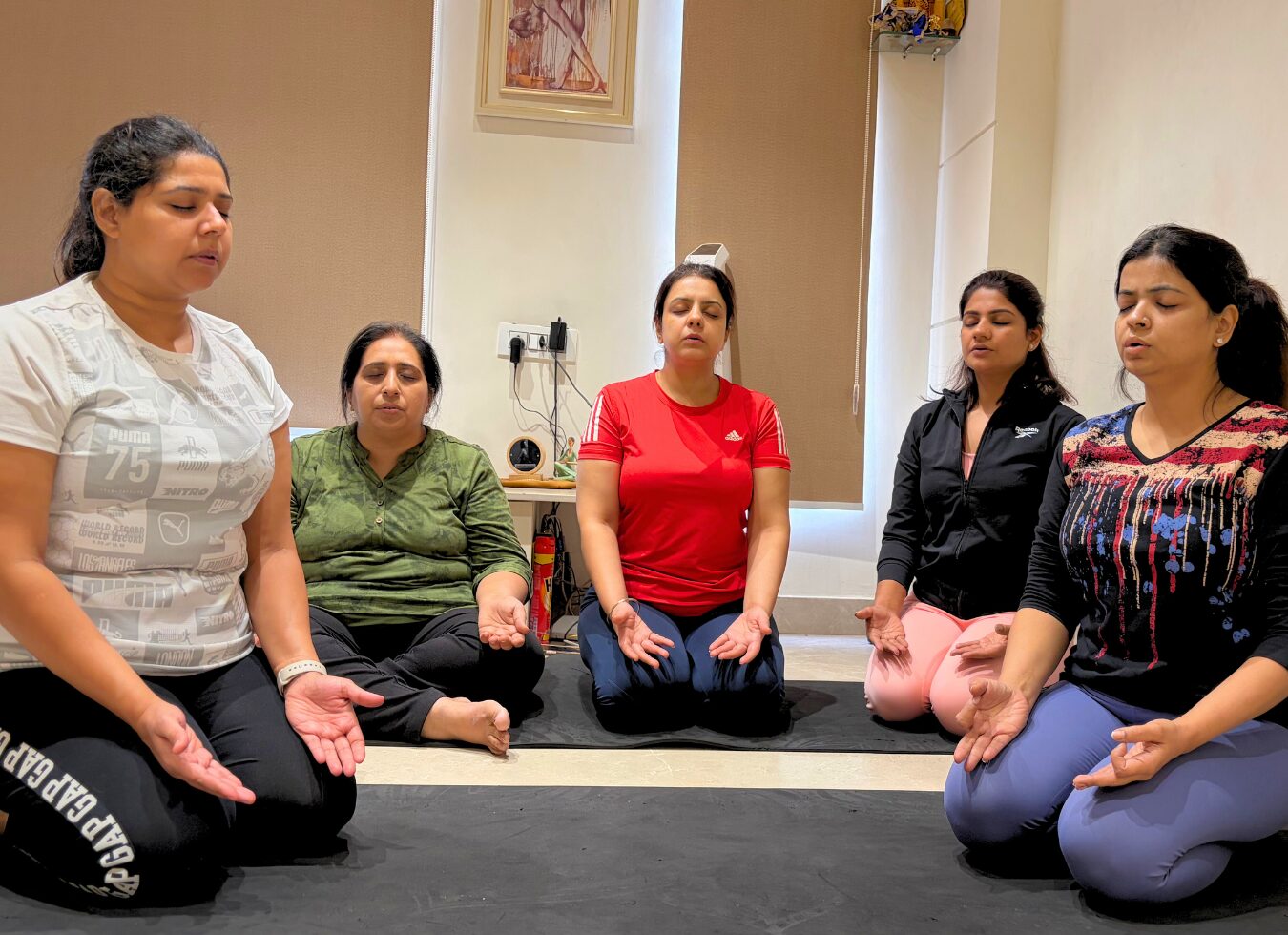 Students seated on mats with their hands in a mudra during a pranayama class at the studio